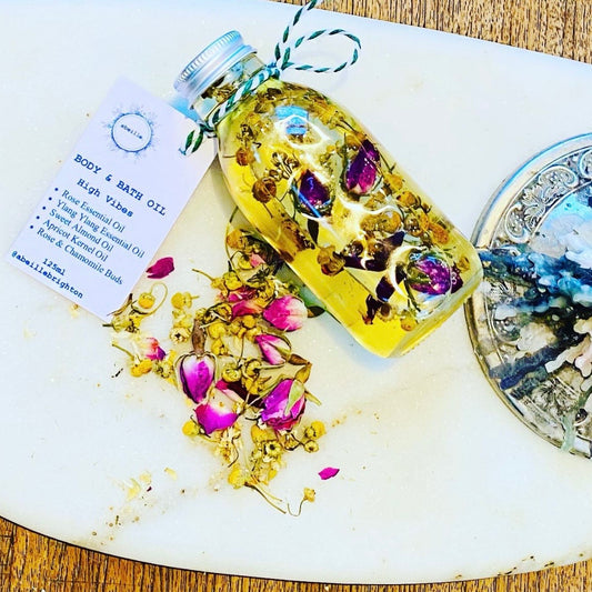 Bottle of body and bath oil with flowers and a label on a white surface.