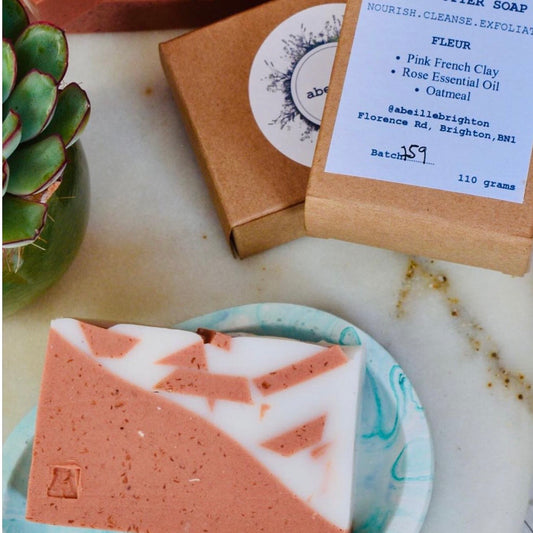 Bar of soap with packaging and a plant on a marble surface