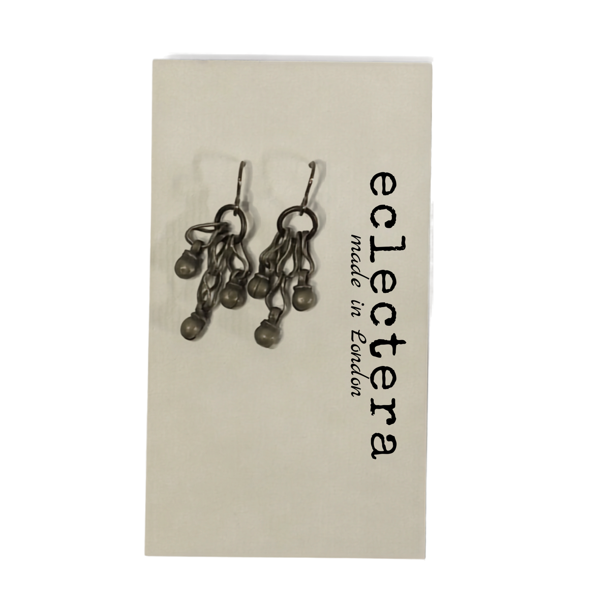 A pair of dark metallic dangle earrings displayed on a cream-colored backing card printed with the brand name 'eclectera' and 'made in London'.