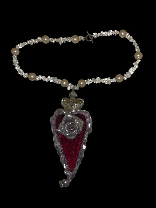 Necklace with a red heart pendant and pearl beads on a plain background