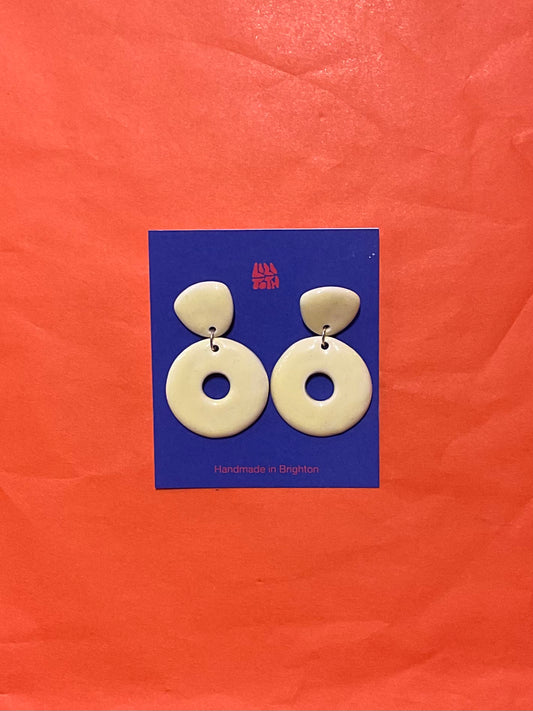 Pair of white circular earrings on a blue card with 'Alfie & Dally' branding against an orange background.