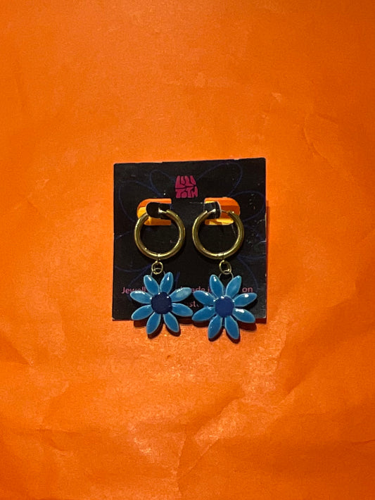 Blue flower-shaped earrings on a black card against an orange background