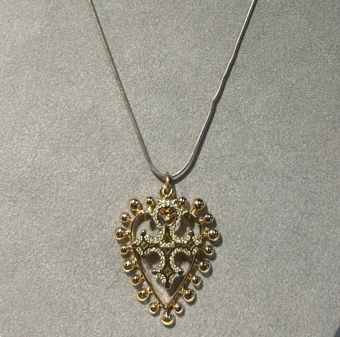 Necklace with a gold heart-shaped pendant on a gray background
