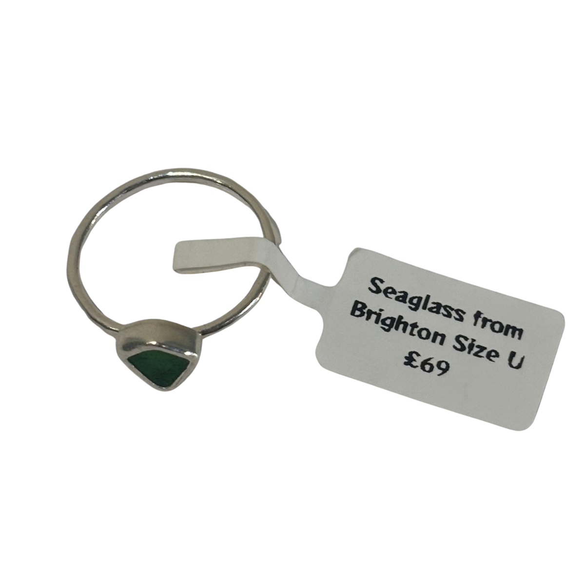 A silver-toned seaglass ring with a small triangular green stone, shown with a white paper size tag that reads 'Seaglass from Brighton Size U £69' on a plain white background.