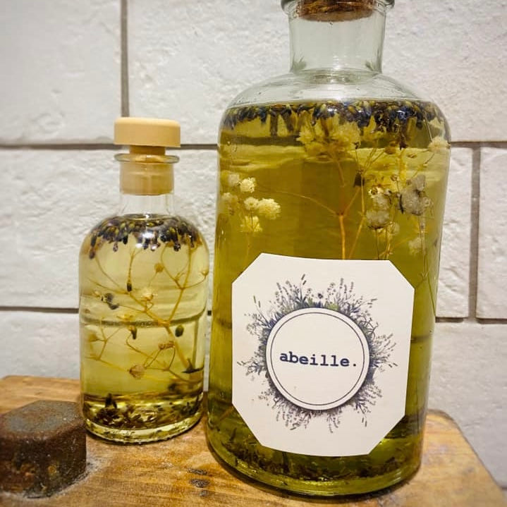 Two glass bottles with floral elements and a label on a wooden surface.
