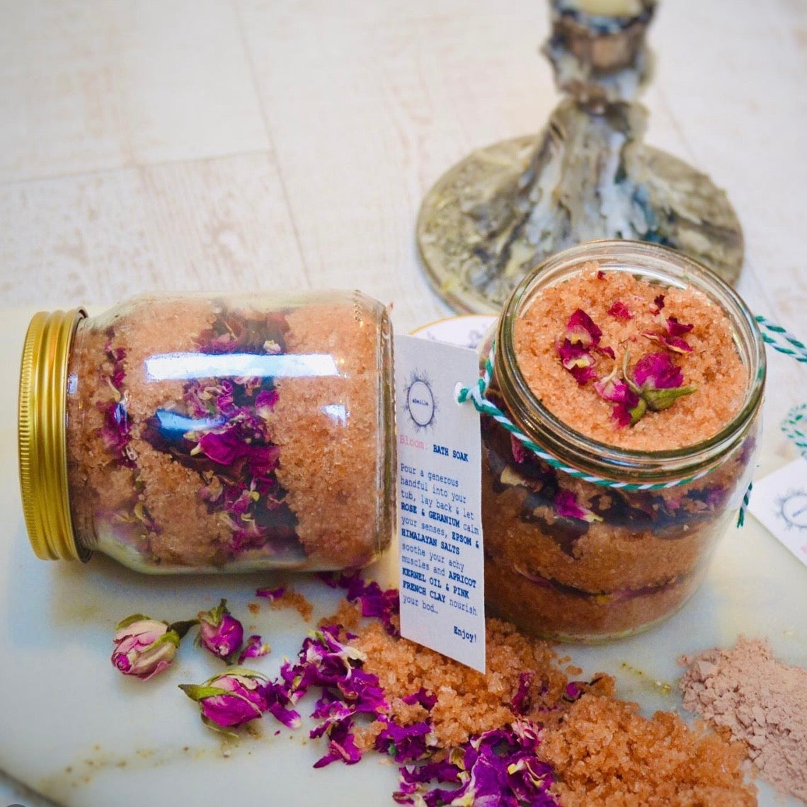 Two jars of bath salts with rose petals on a marble surface