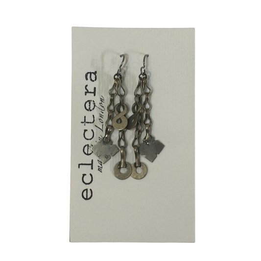 A pair of handmade dangle earrings made of silver-toned chains, key rings, and clover charms, displayed on a light gray card printed with the brand name 'eclectera'.