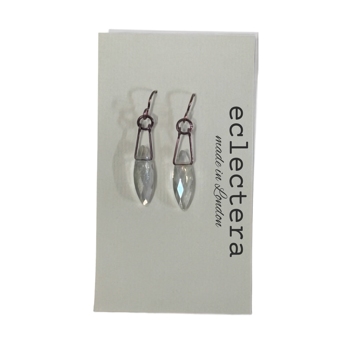 A pair of silver-toned drop earrings with clear faceted teardrop crystals, displayed on a white brand card for 'eclectera made in London'.