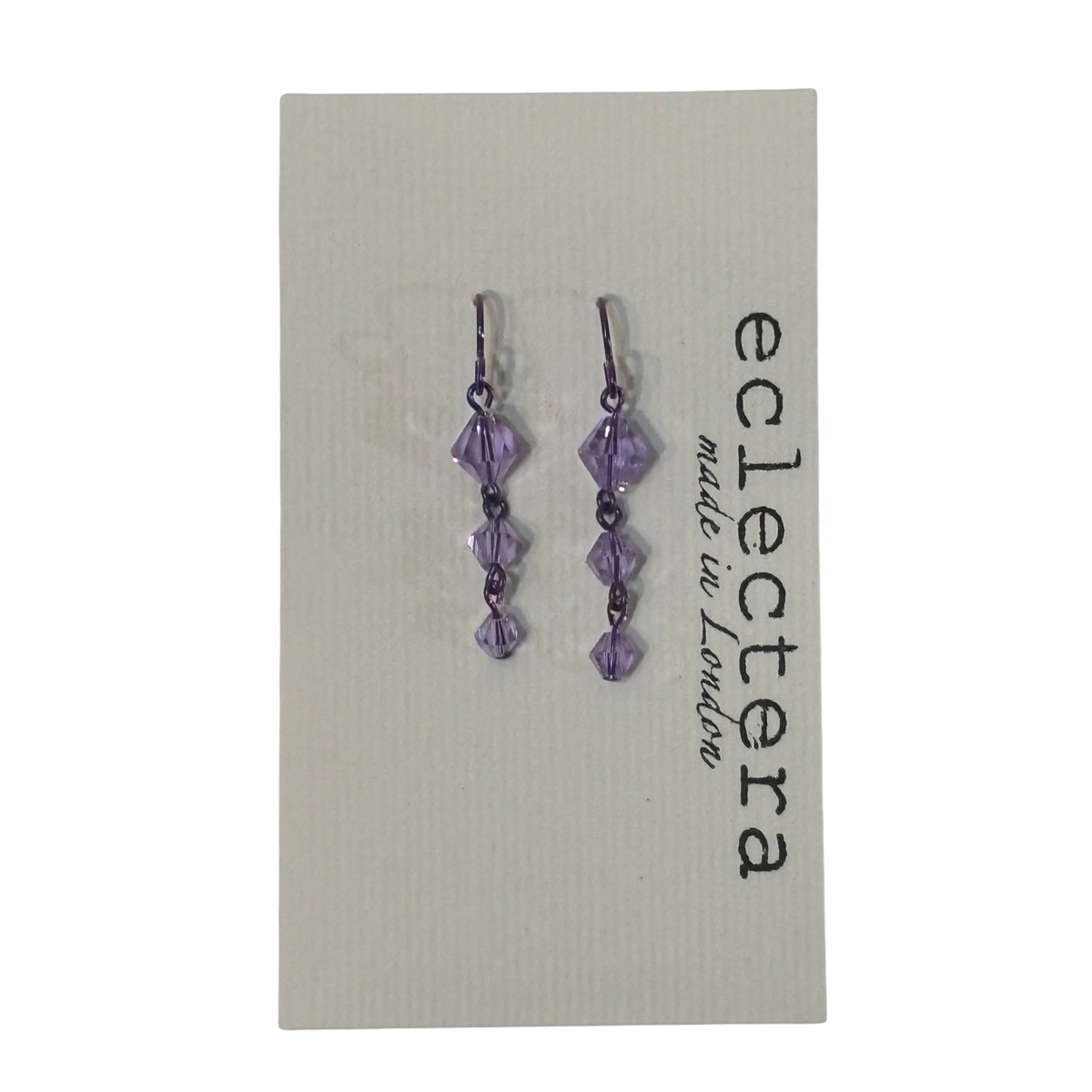 A pair of dangling earrings with faceted purple beads on a light gray display card. The card has the brand name 'eclectera' printed vertically on the right side.