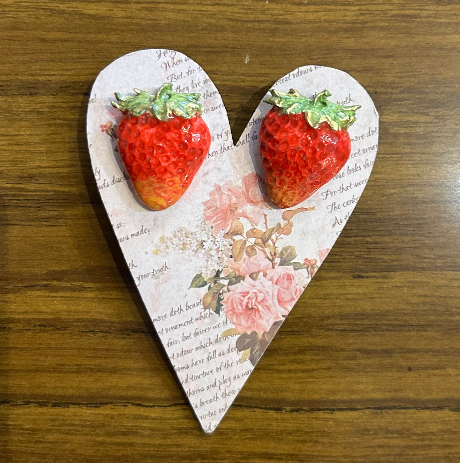 Heart-shaped wooden block with strawberry designs on a wooden surface
