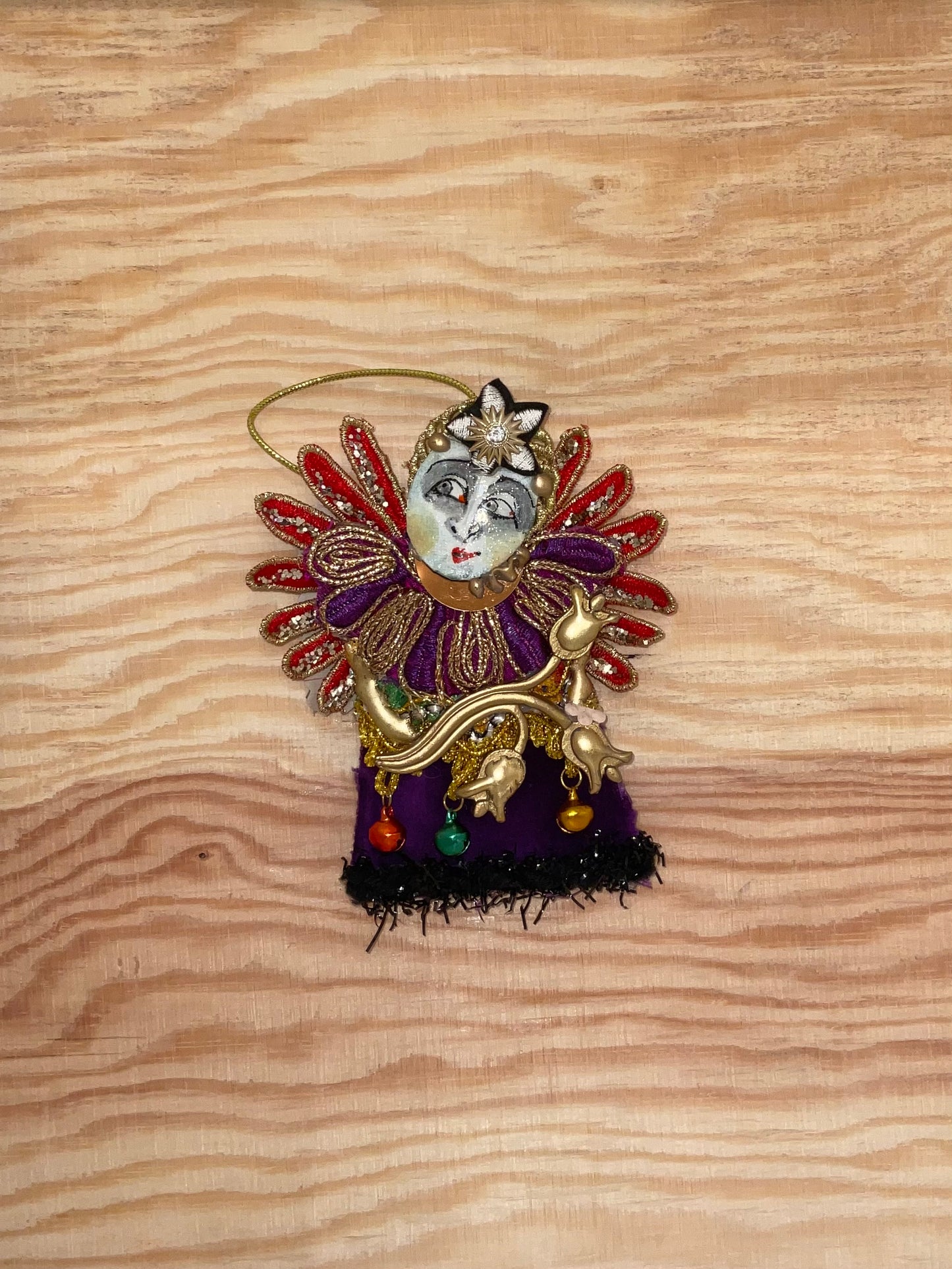 Decorative ornament with face and colorful details on a wooden surface