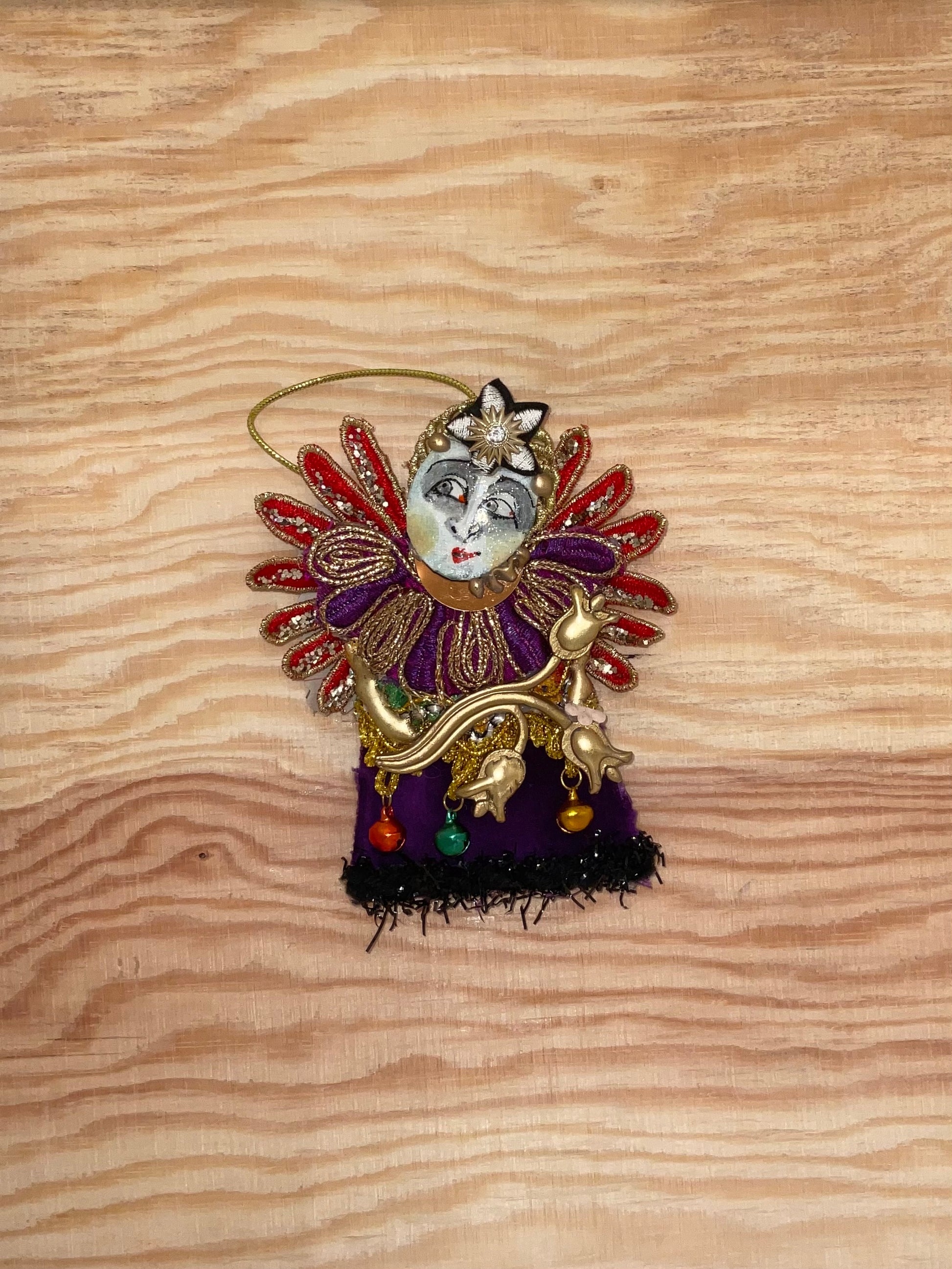 Decorative ornament with face and colorful details on a wooden surface