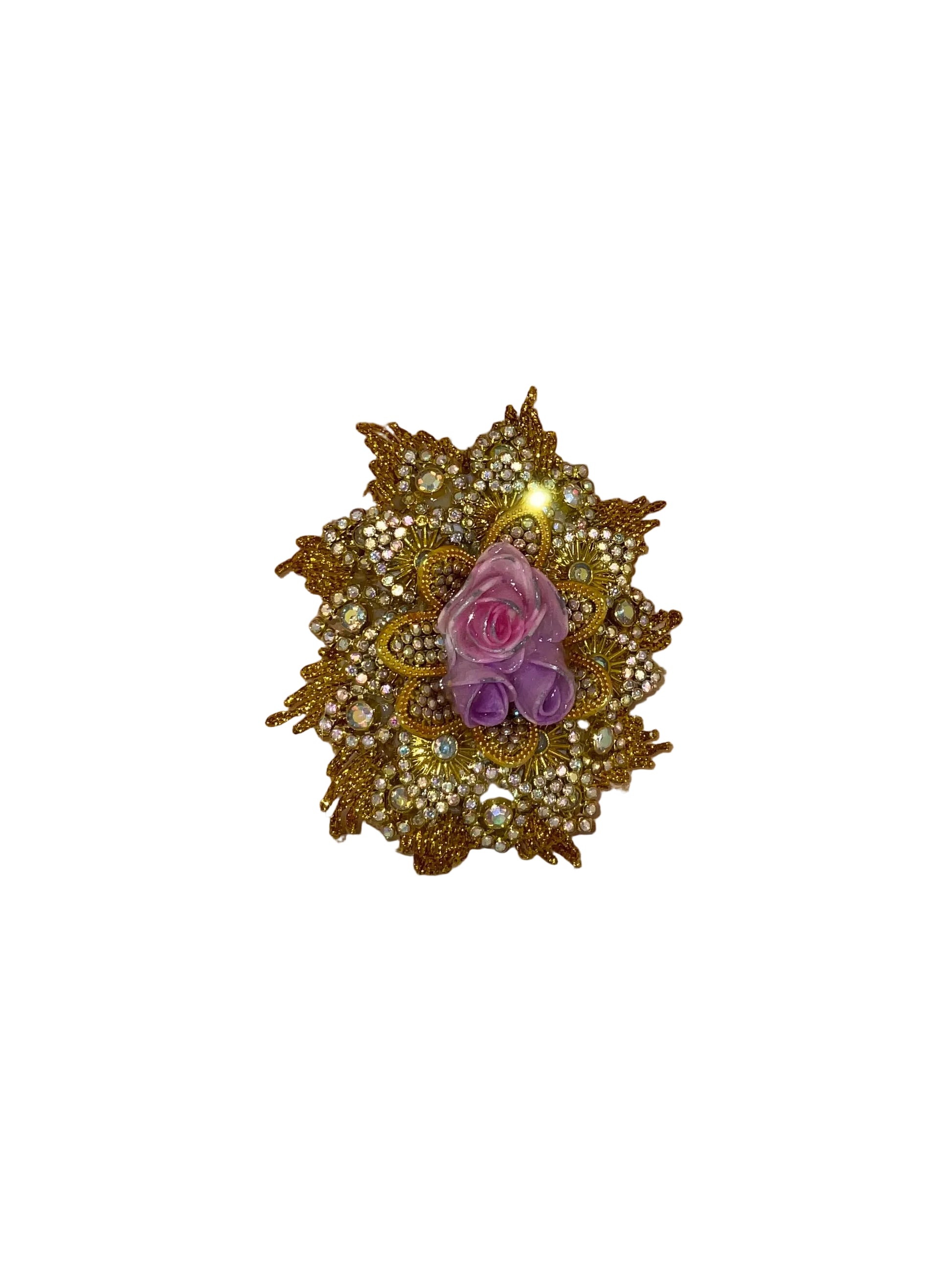 Decorative brooch with gold detailing and a pink and purple flower on a wooden surface.