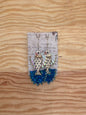 Fish-shaped earrings with blue accents on a wooden surface