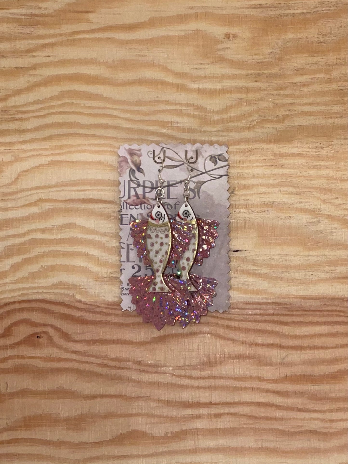 Decorative fish earrings on a wooden surface