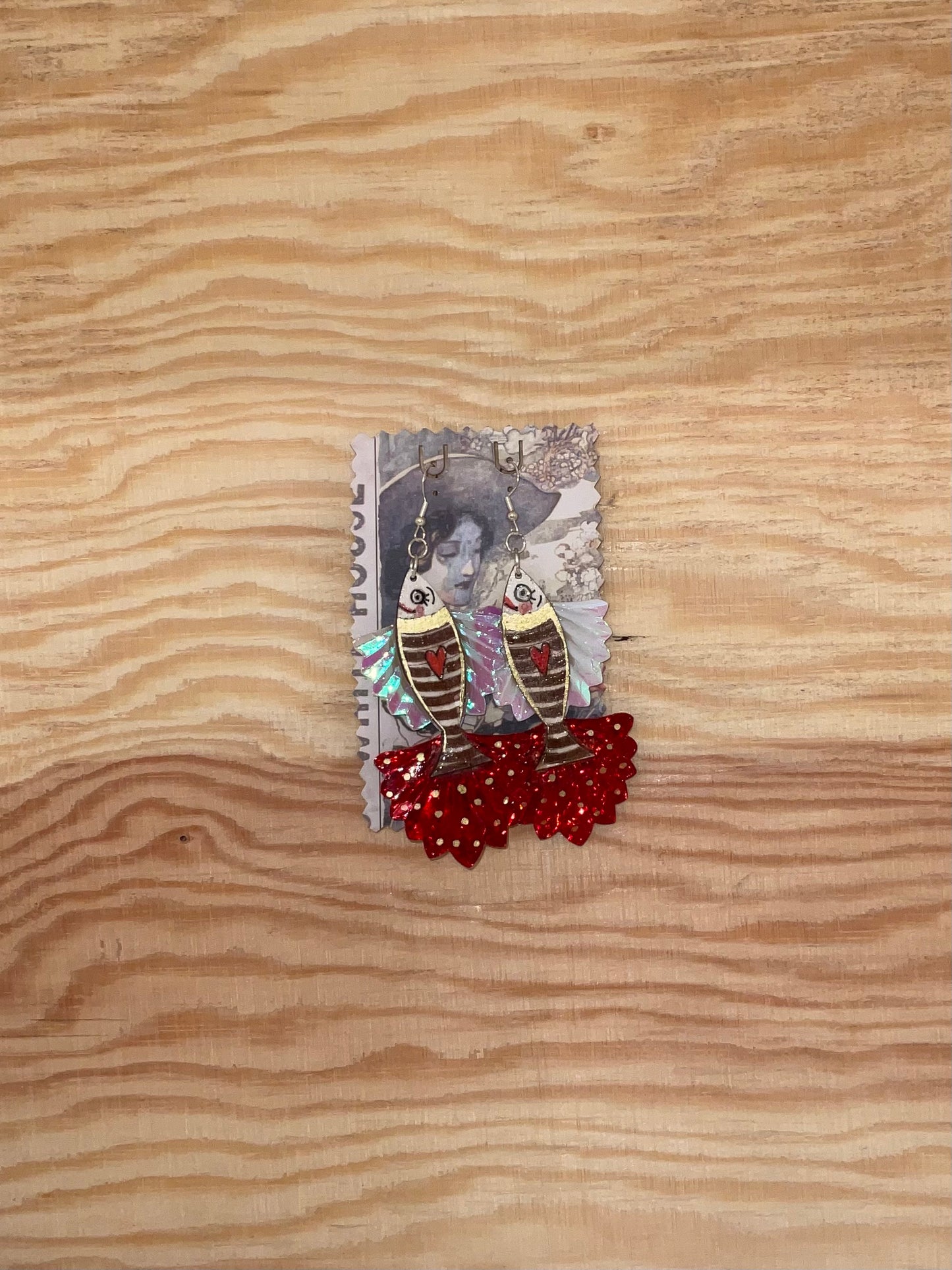 Decorative brooch with earrings and red beads on a wooden surface