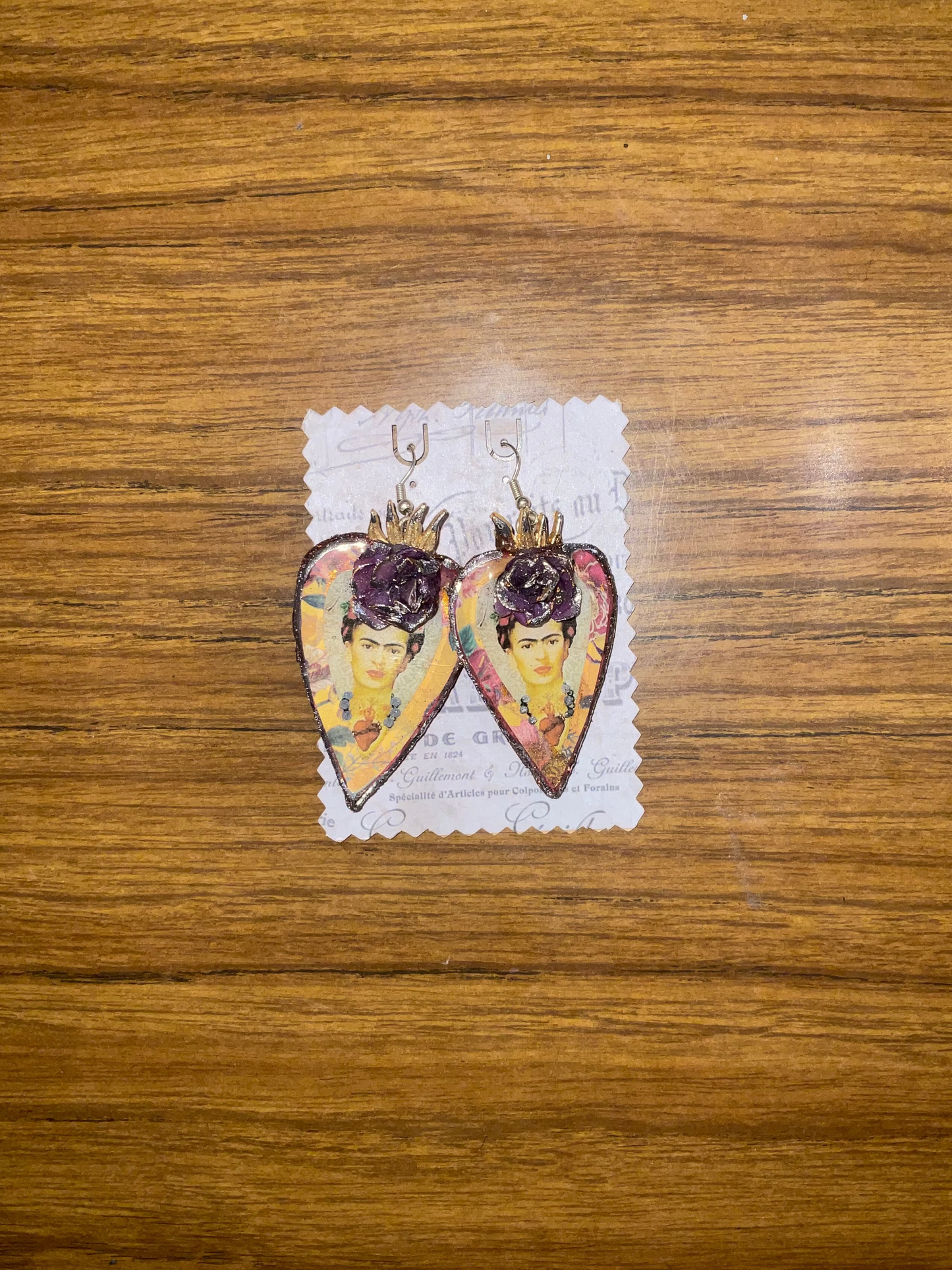 Heart-shaped earrings with a decorative design on a wooden surface