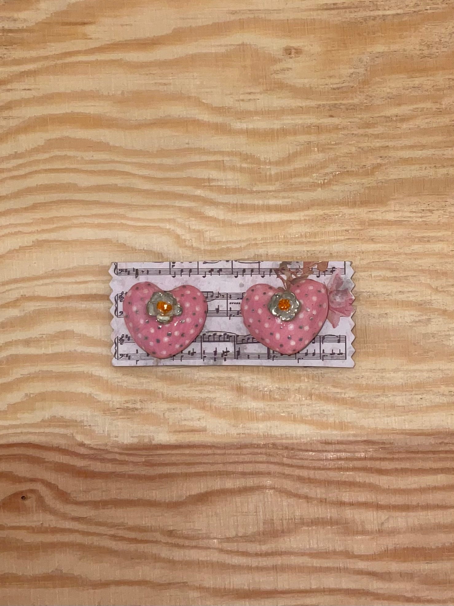 Heart-shaped hair clips on a card with music notes on a wooden surface