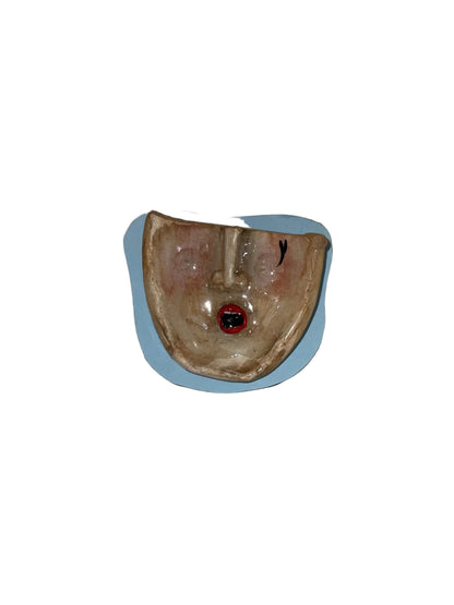 Ceramic face sculpture on a wooden surface