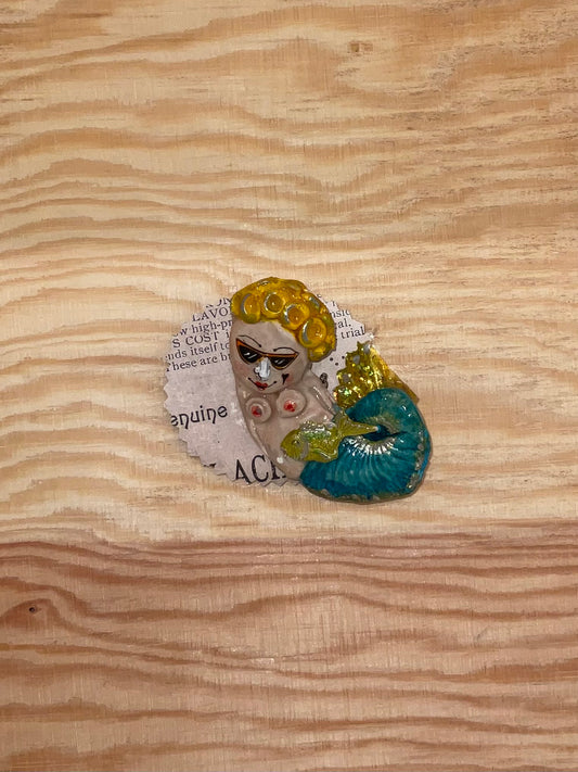 Decorative brooch with a vintage-style face design on a wooden surface