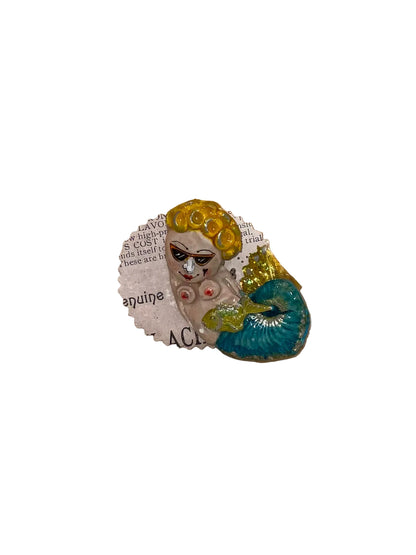 Decorative brooch with a vintage-style face design on a wooden surface