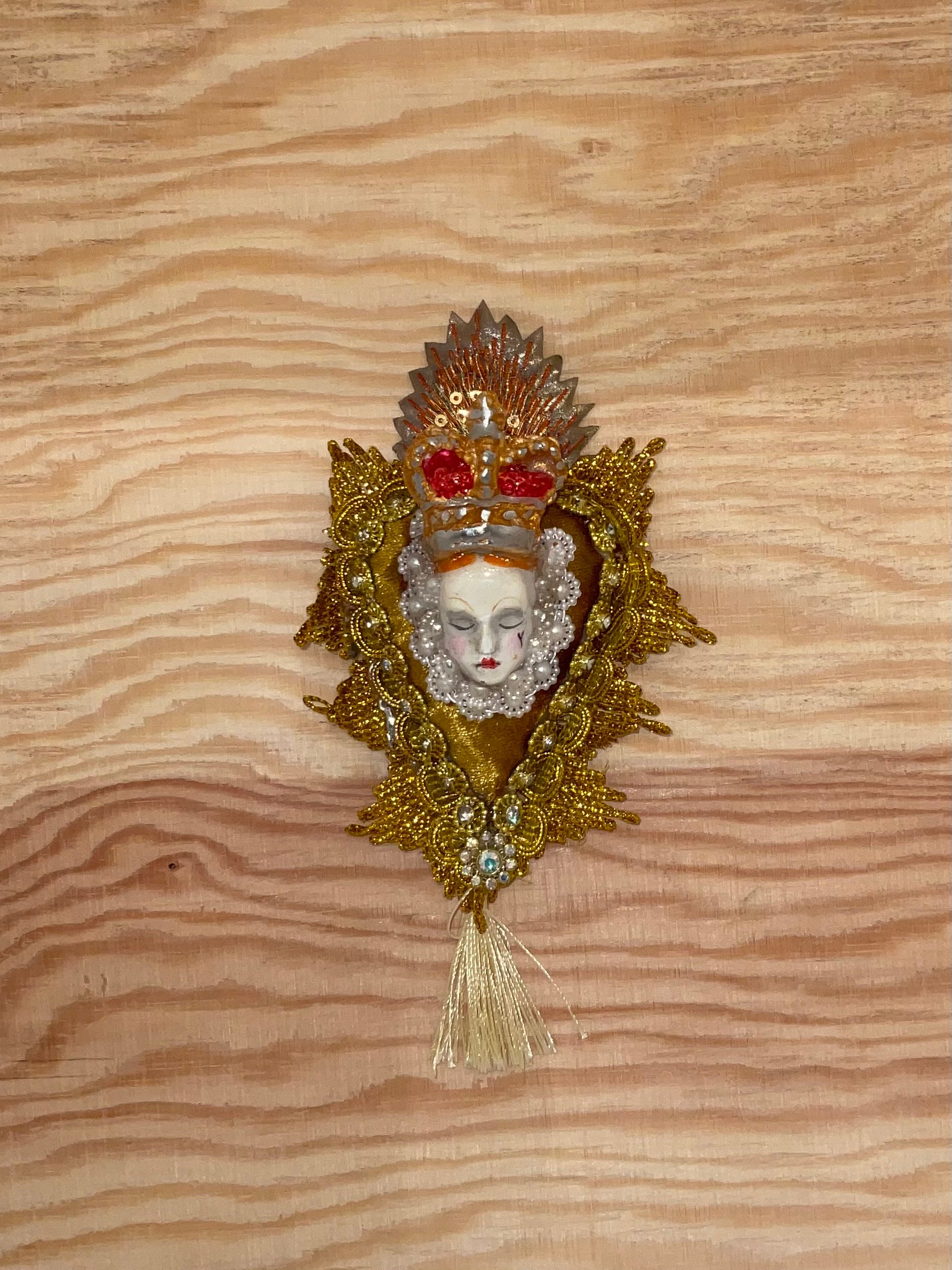 Decorative brooch with a face design on a wooden surface