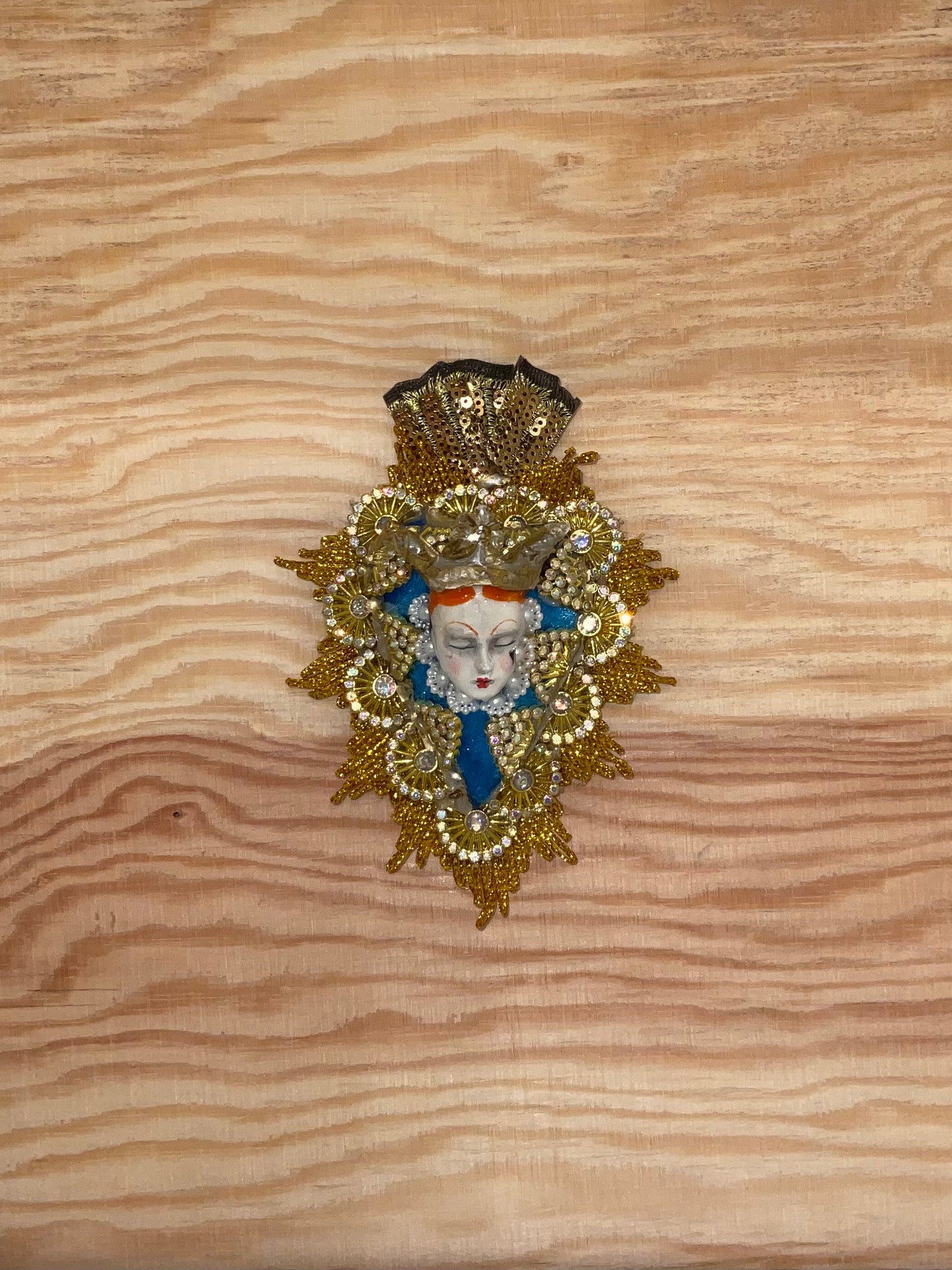 Decorative brooch with a face design on a wooden surface