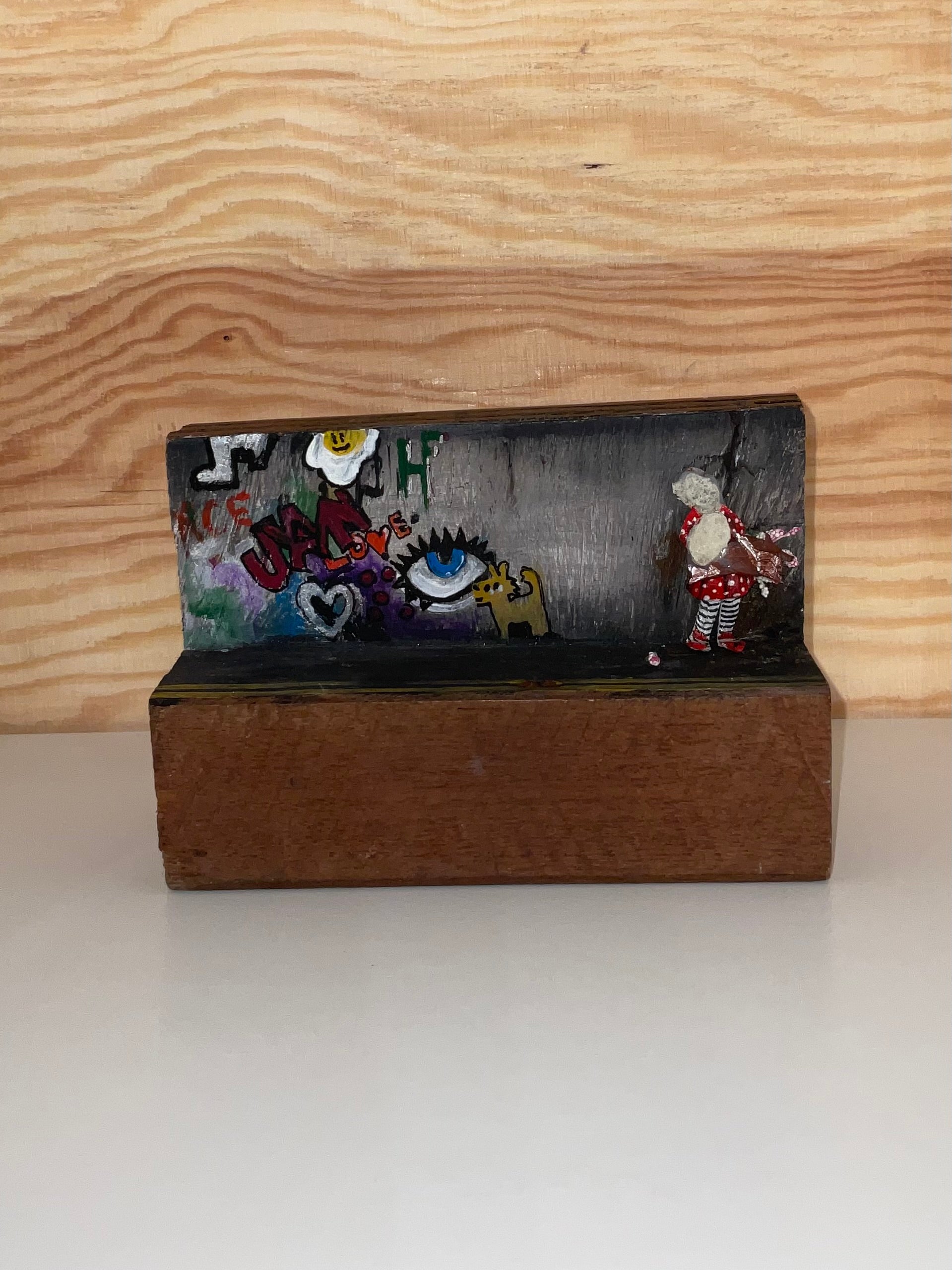 Decorative clutch with embroidered designs on a wooden stand against a wooden background