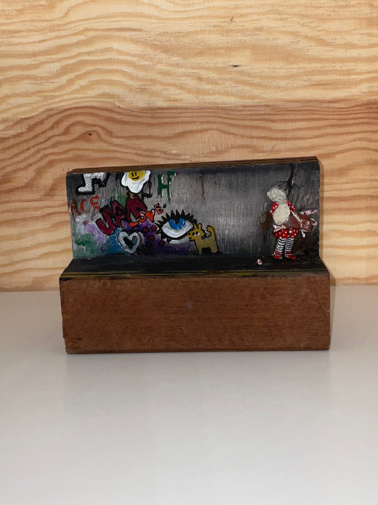 Decorative clutch with embroidered designs on a wooden stand against a wooden background