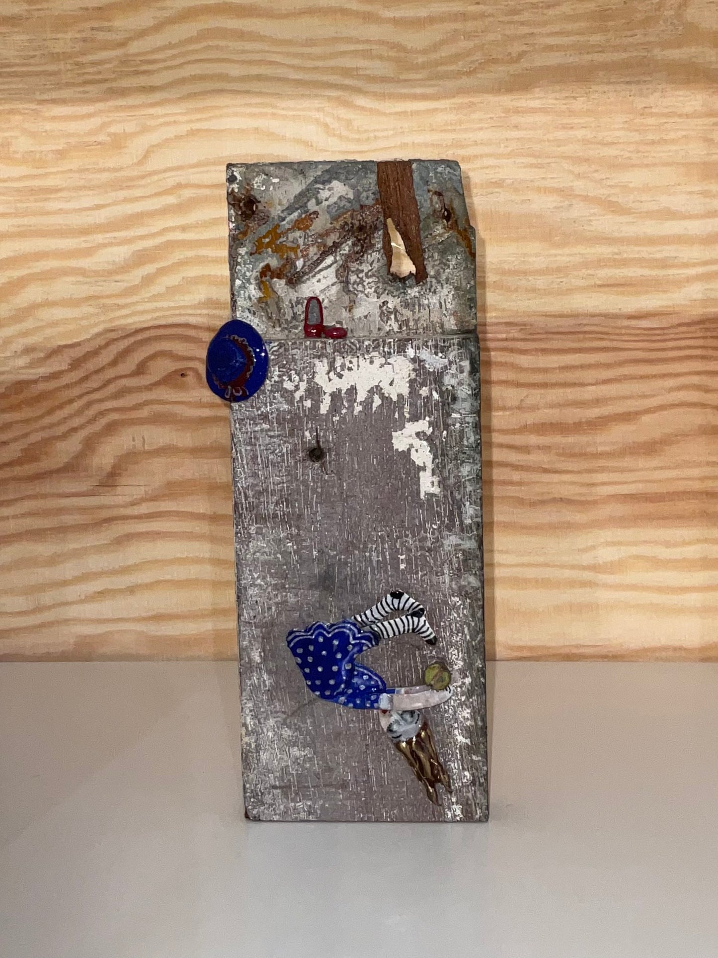 Decorative wall piece with various small objects on a wooden surface