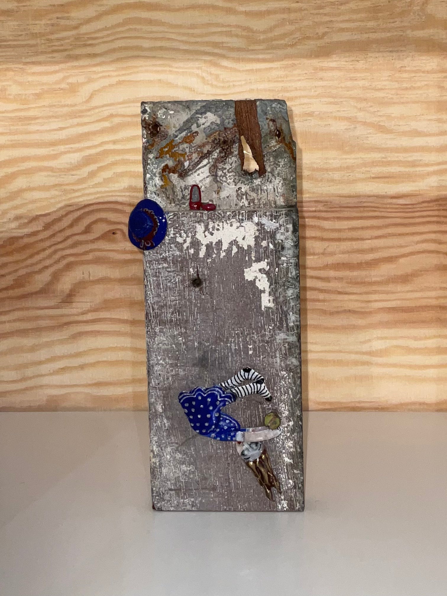 Decorative wall piece with various small objects on a wooden surface