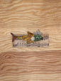 Decorative fish brooch with gemstones on a piece of sheet music, placed on a wooden surface.