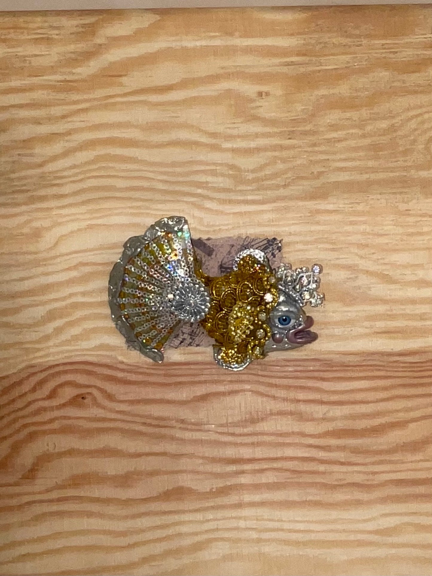 Decorative fish figurine with glittery scales on a wooden surface