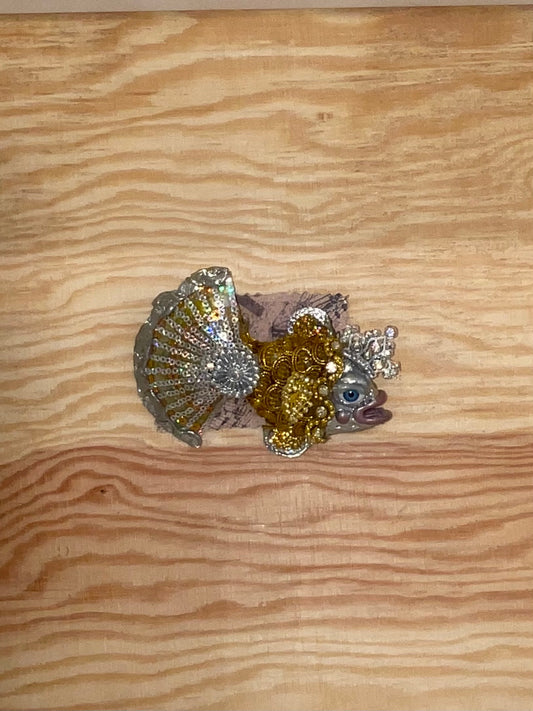 Decorative fish figurine with glittery scales on a wooden surface