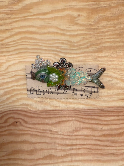 Decorative fish-shaped object with floral elements and musical notes on a wooden surface