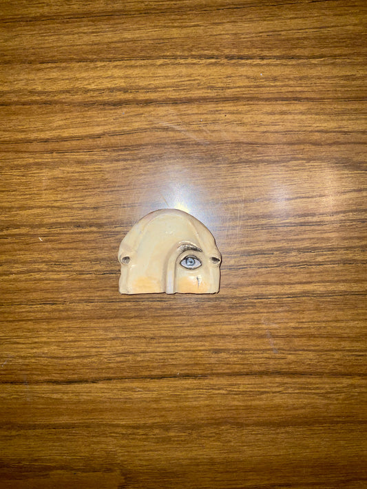 Small ceramic face figurine on a wooden surface