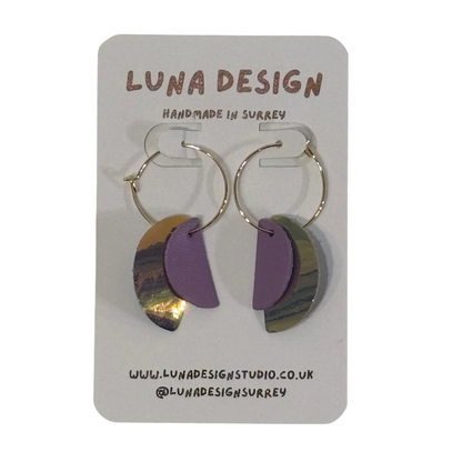 A pair of handmade hoop earrings by Luna Design, featuring purple and iridescent gold crescent moon shapes on gold hoops, displayed on a white backing card.
