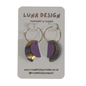 A pair of handmade hoop earrings by Luna Design, featuring purple and iridescent gold crescent moon shapes on gold hoops, displayed on a white backing card.