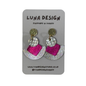 A pair of handmade statement earrings by Luna Design, featuring textured gold-tone studs, silver-tone circular discs, and fan-shaped drops in hot pink and silver glitter, displayed on a grey card backing.