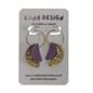 A pair of handmade crescent-shaped hoop earrings by Luna Design, featuring purple faux leather and iridescent gold foil sections, displayed on a grey cardboard backing card.