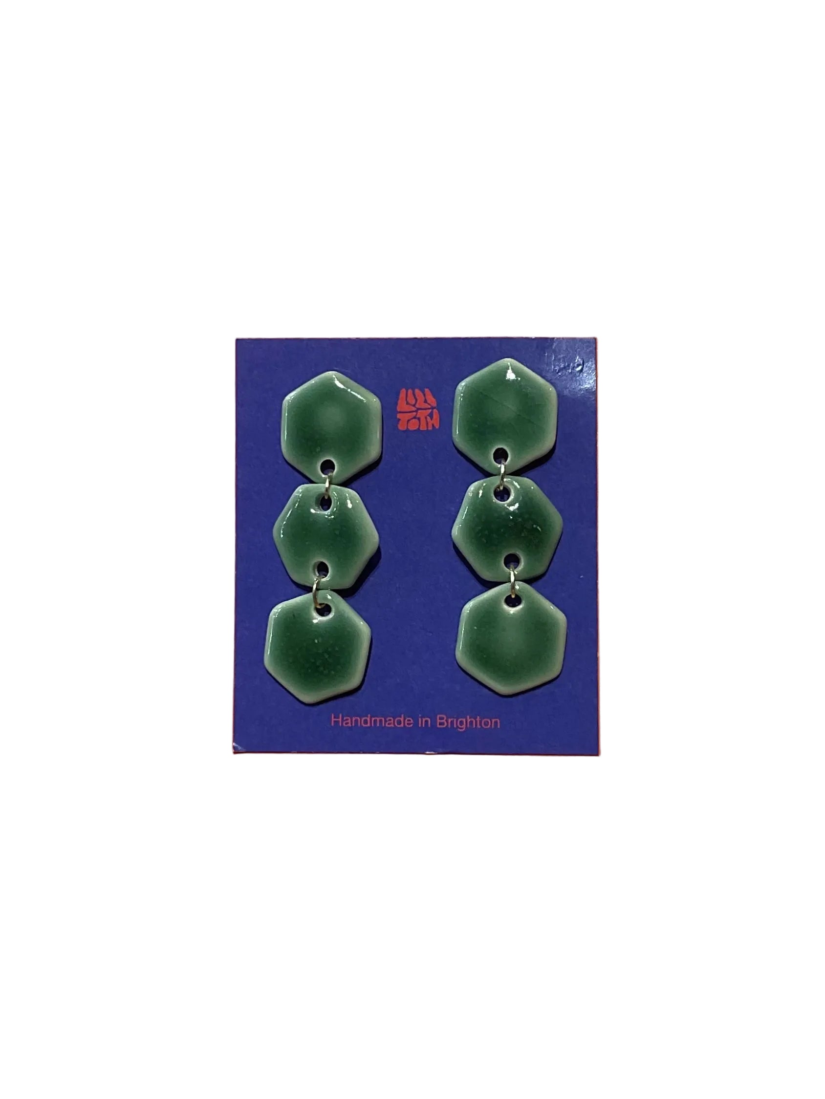 Green earrings on a blue card with 'Handmade in Brighton' text, against an orange background