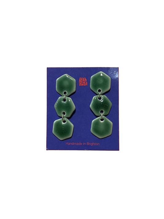 Green earrings on a blue card with 'Handmade in Brighton' text, against an orange background