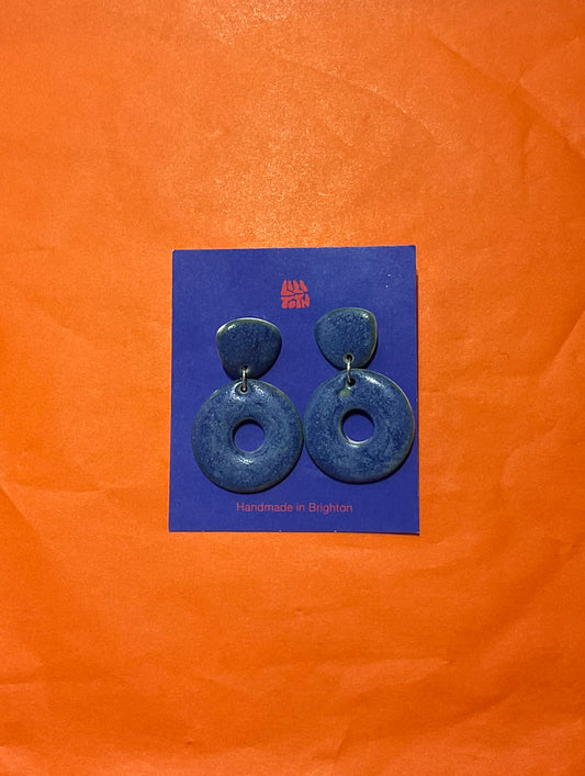 Blue earrings on a blue card with 'Handmade in Brighton' text, against an orange background