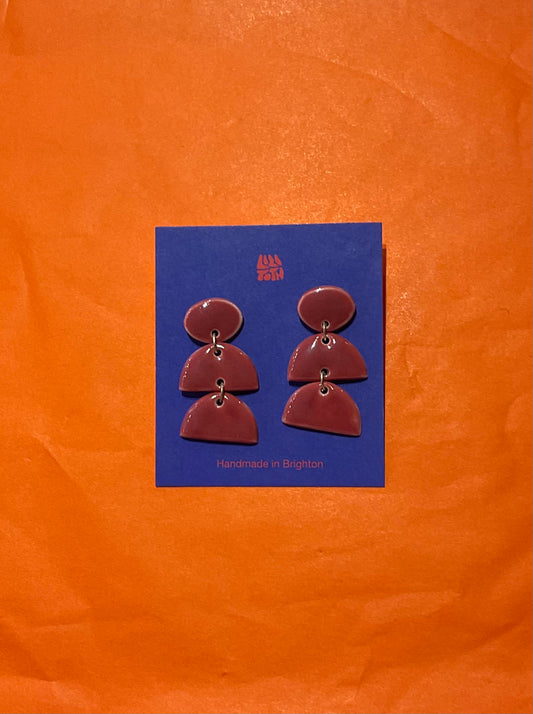 Pair of earrings on a blue card with 'All the Luck' branding against an orange background