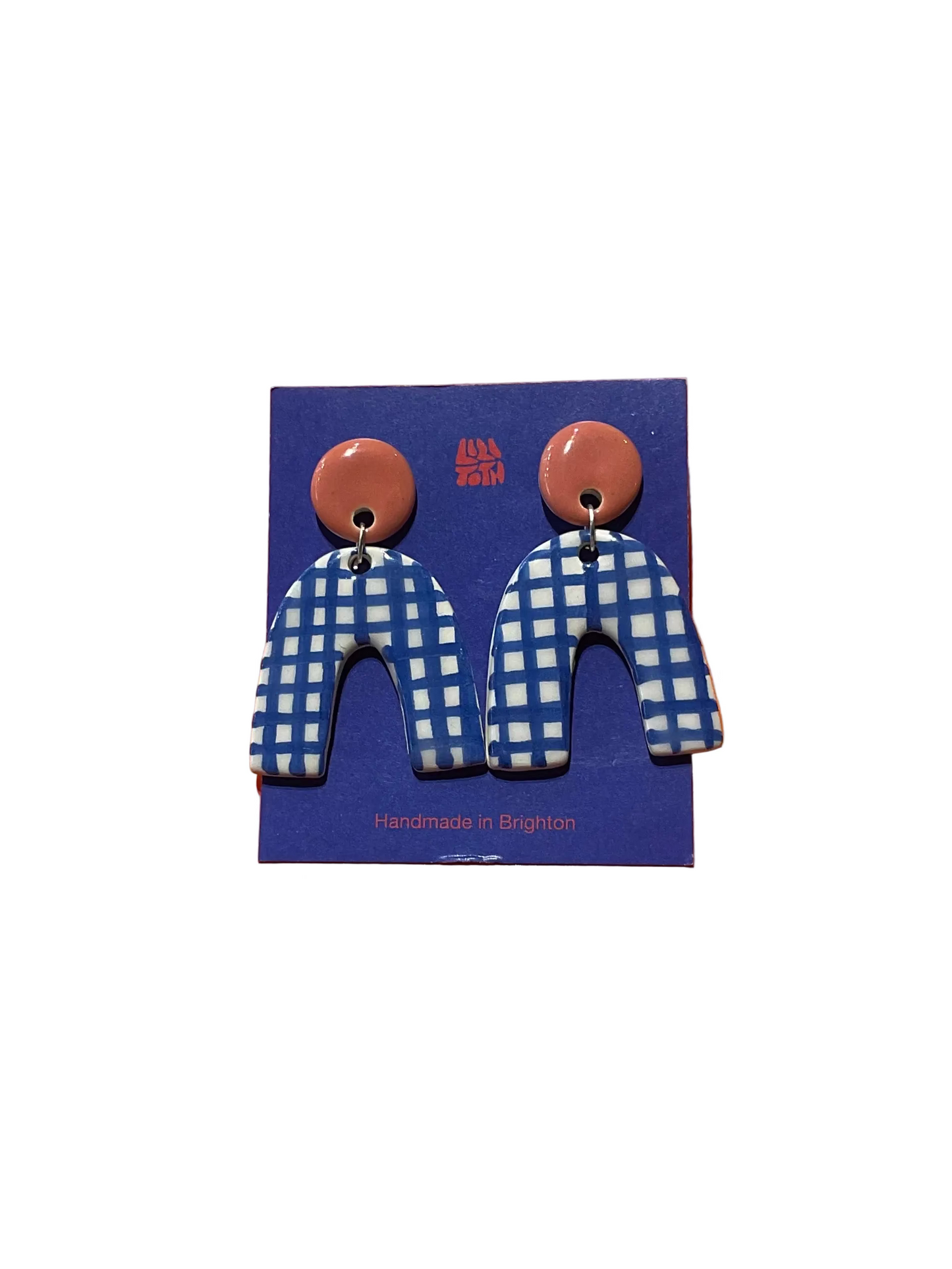 Earrings with blue and white checkered design on a blue card against an orange background