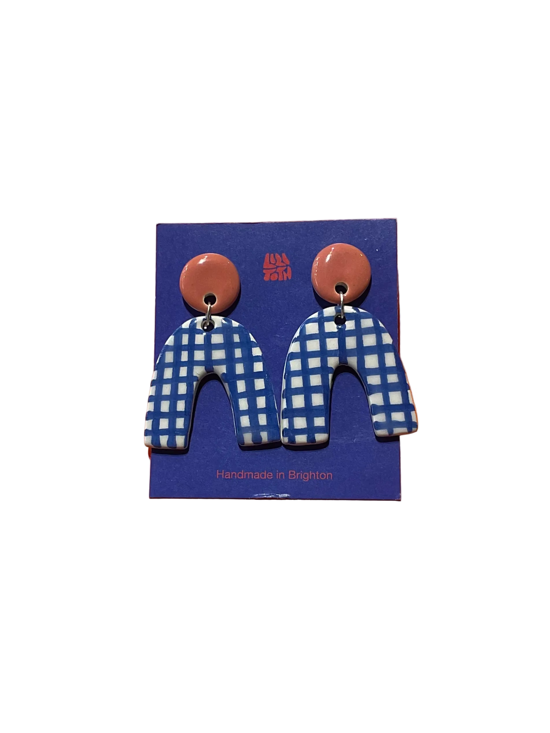 Earrings with blue and white checkered design on a blue card against an orange background