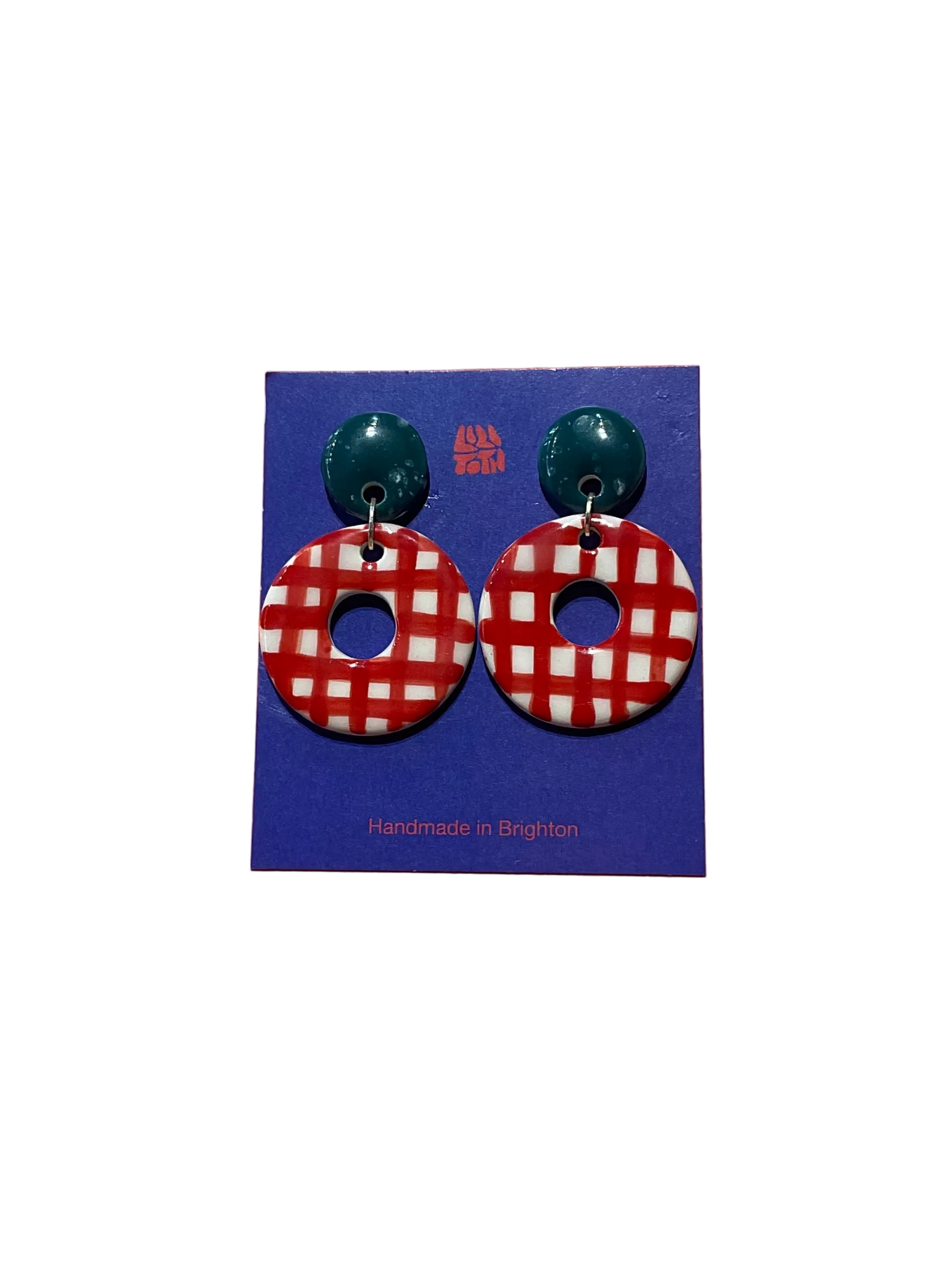 Red and white checkered earrings on a blue card with green posts, against an orange background.