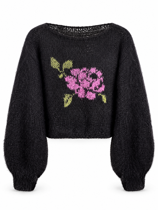 A black fuzzy cropped sweater with a pink and green floral knit pattern on the front, displayed against a plain white background.