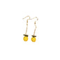 Pineapple-shaped earrings on a wooden tray with a white fabric background