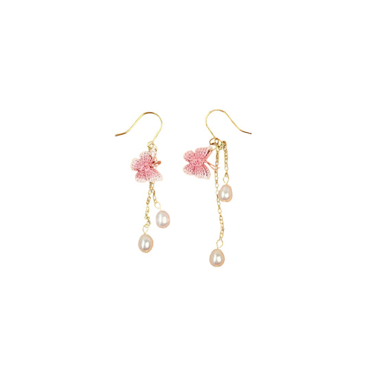 Pair of floral earrings with pink flowers and pearl drops on a wooden tray.